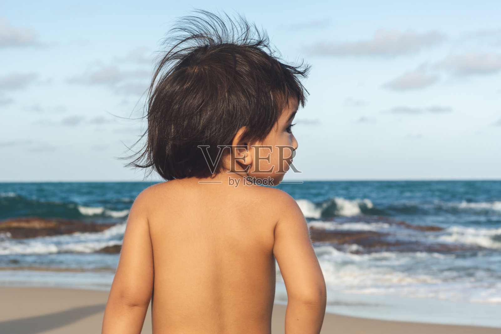 可爱的亚洲小男孩在海滩上看海的肖像照片摄影图片