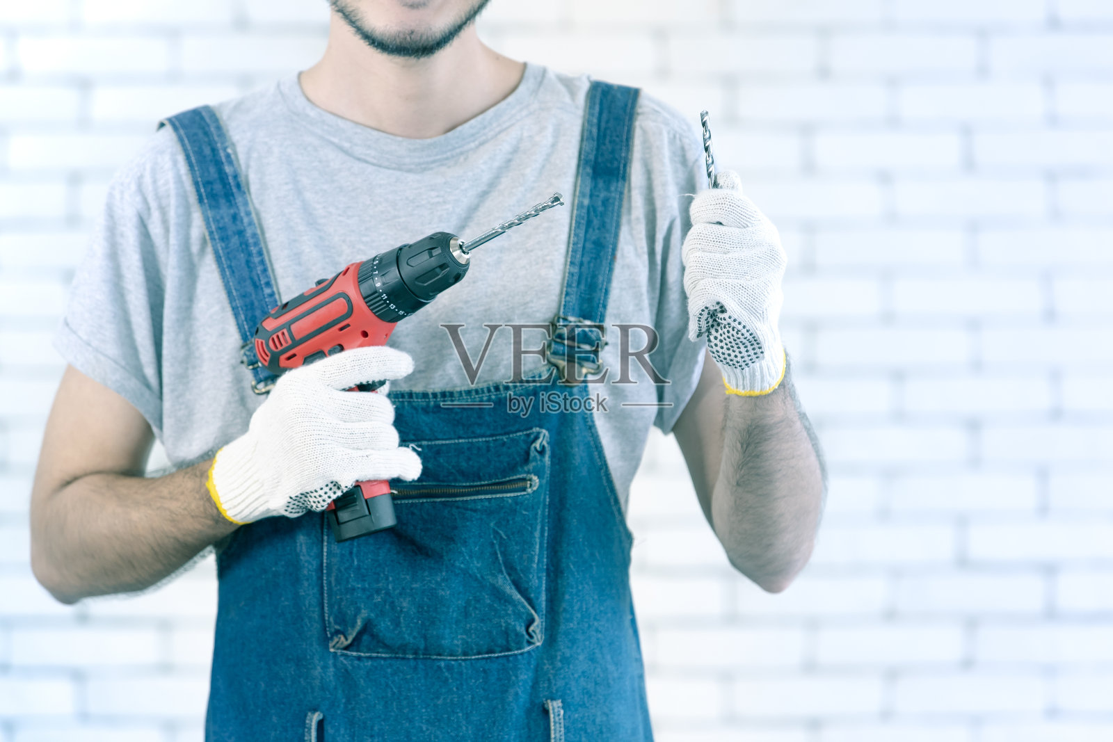 手拿钻机的杂工。照片摄影图片