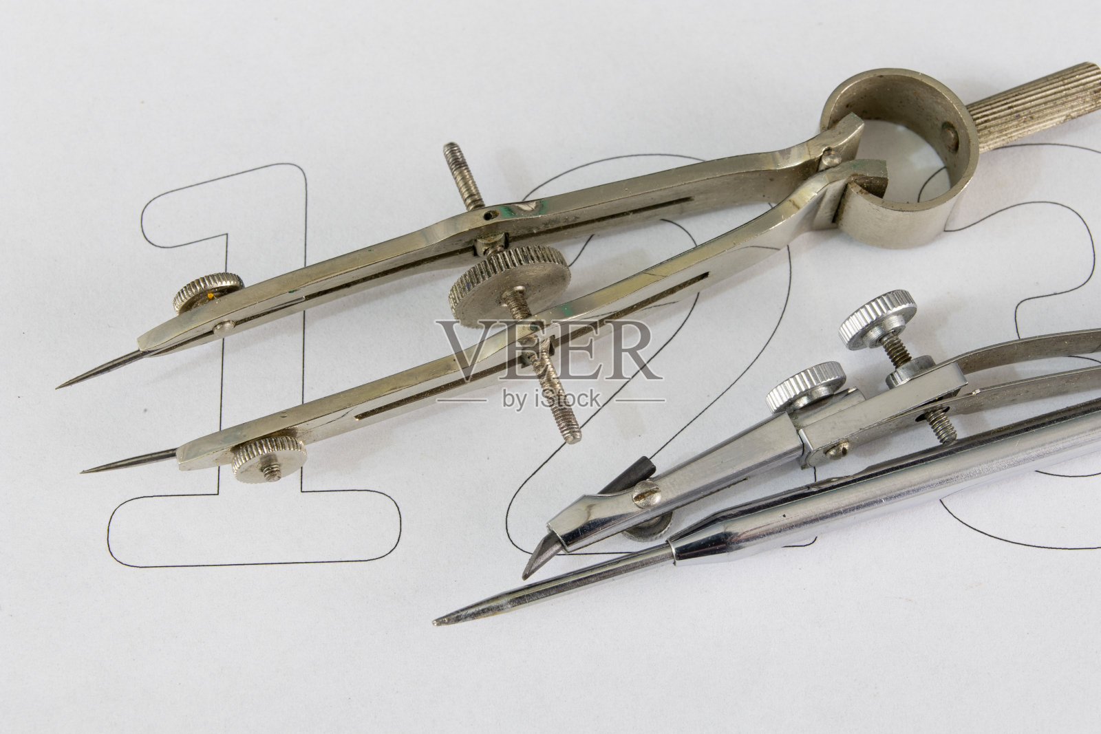 一个在白纸上画圆圈的同伴。用于绘制技术图纸的绘图附件。光背景。照片摄影图片