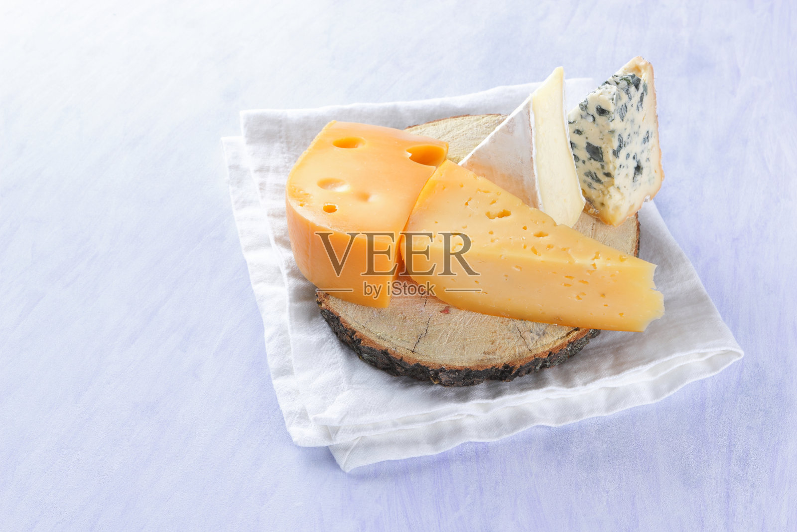 卡芒贝尔奶酪，硬的黄色奶酪和蓝奶酪在木板上。白色餐巾上有各种各样的奶酪。极简主义风格的Dorblu和软奶酪。乳制品照片摄影图片