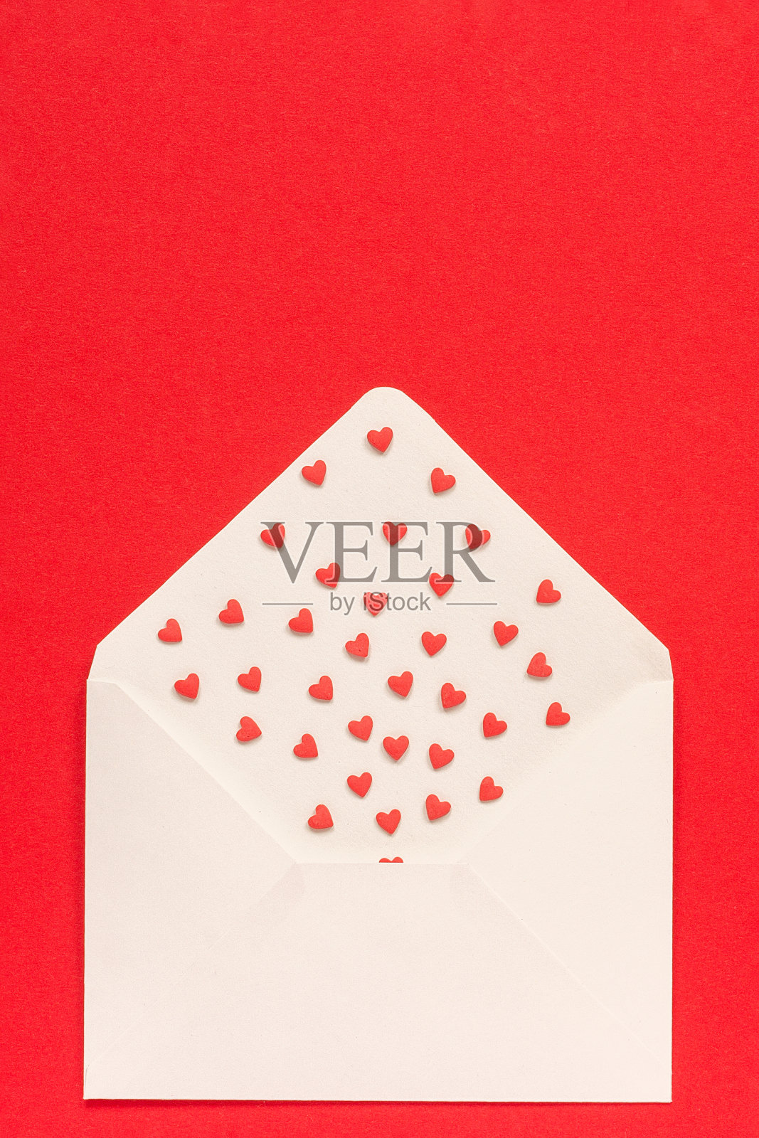 红色糖果撒心形糖果飞出白色的信封在红色的背景。顶部视图复制空间的文本。概念情人节和情人节卡片。礼物，带着爱的信息照片摄影图片