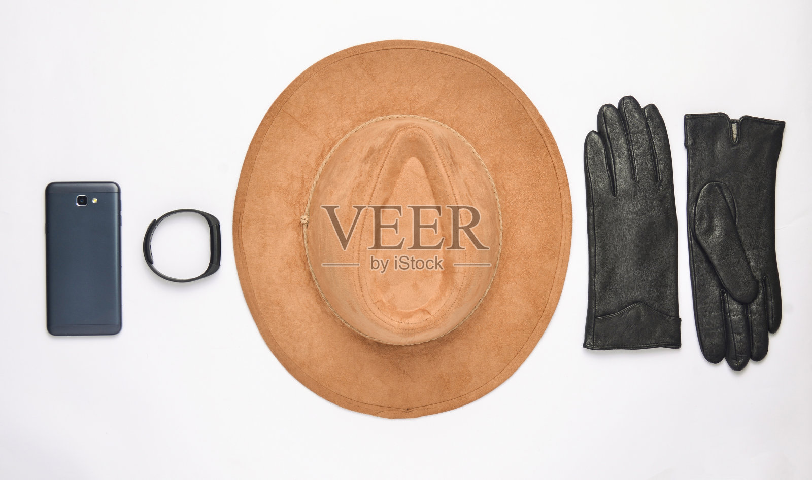 白色背景上的女性配件和小玩意。帽子，手套，智能手机，智能手表。秋天春天收藏。前视图。平躺照片摄影图片