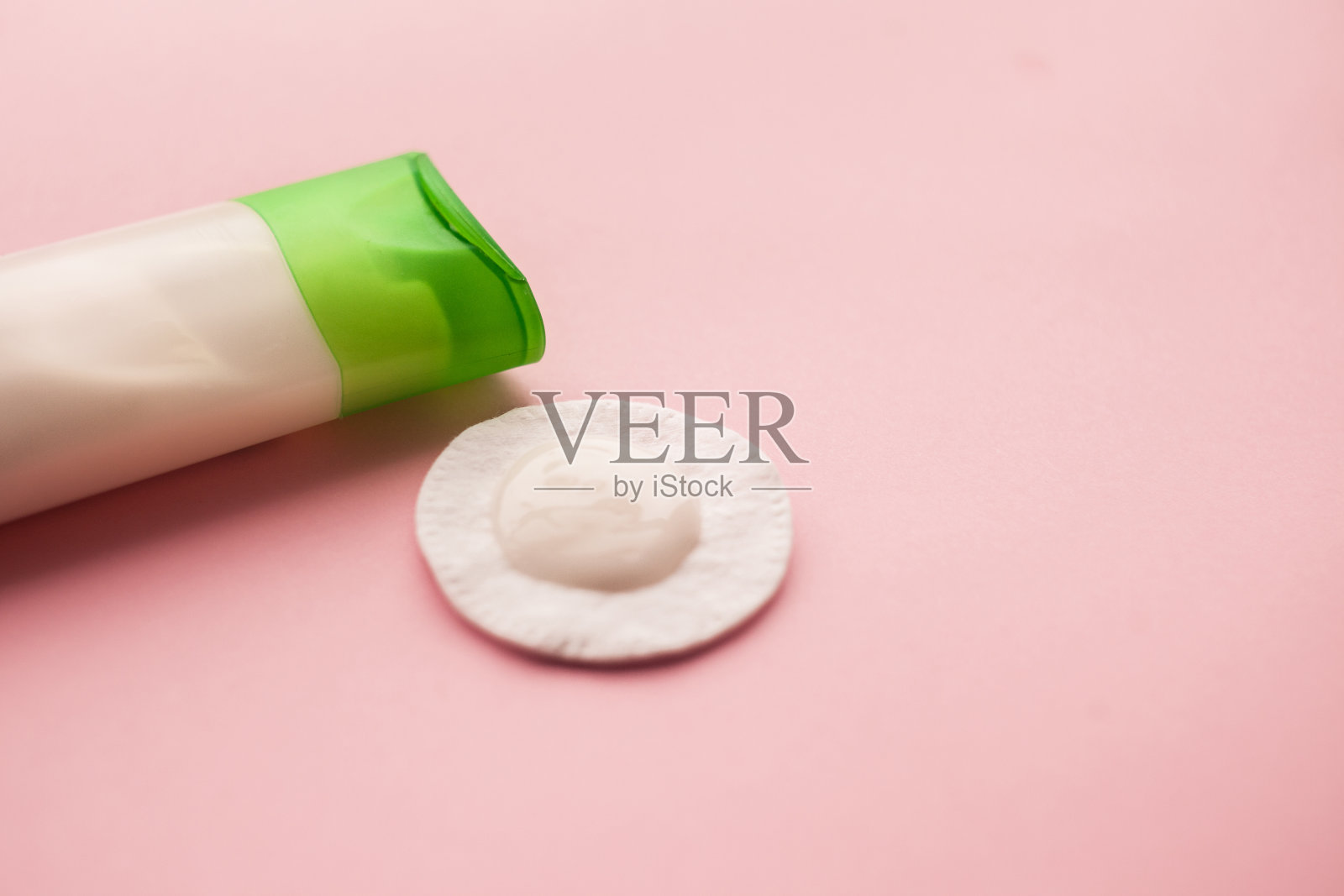 洁面乳和化妆棉。粉红色的背景。卸妆。皮肤护理。前视图。有选择性的重点。照片摄影图片