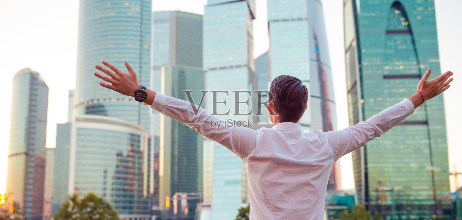 后视图的商人看复印空间，而站在玻璃摩天大楼照片摄影图片