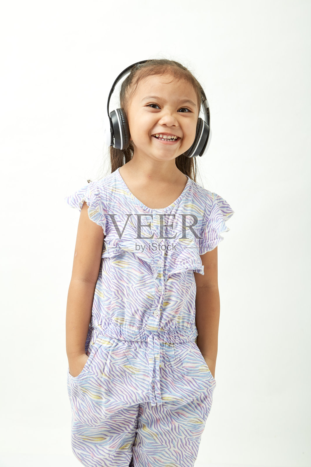 可爱小女孩戴着耳机听音乐的肖像照片摄影图片
