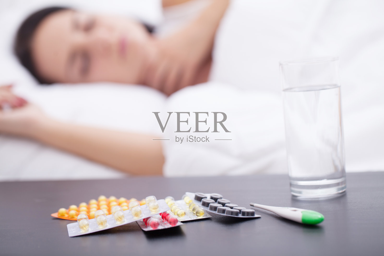 睡着的不健康女人和床头柜上的药片照片摄影图片