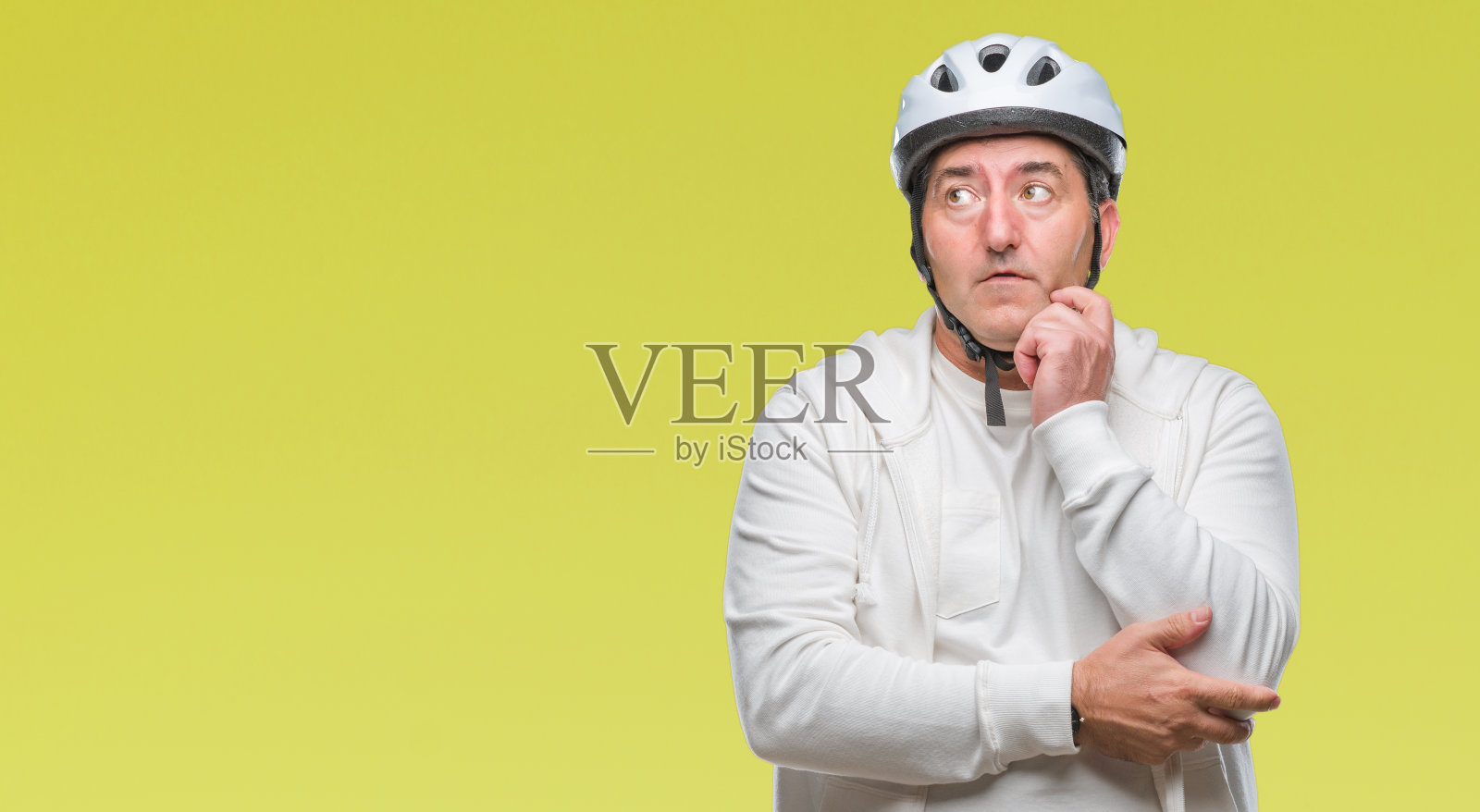 帅气的资深骑车人戴着自行车头盔越过孤立的背景严肃地面对思考问题，非常困惑的想法照片摄影图片