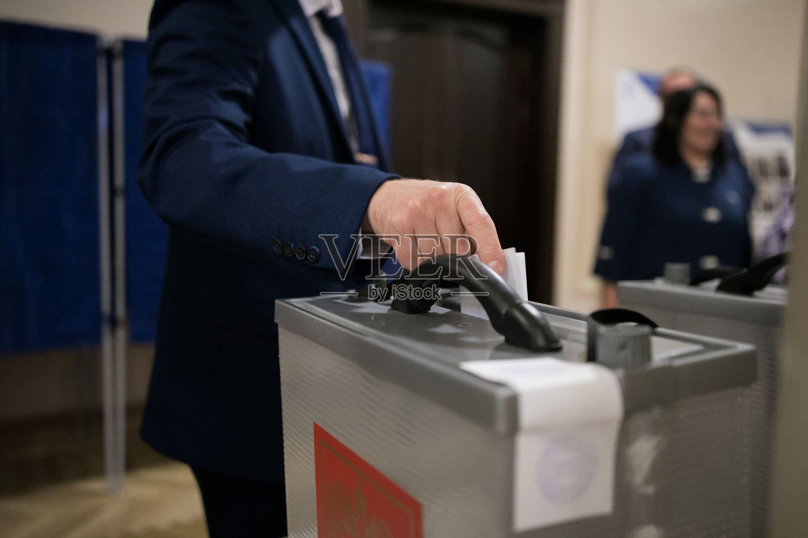 投票时在投票站投选票的人的手。照片摄影图片