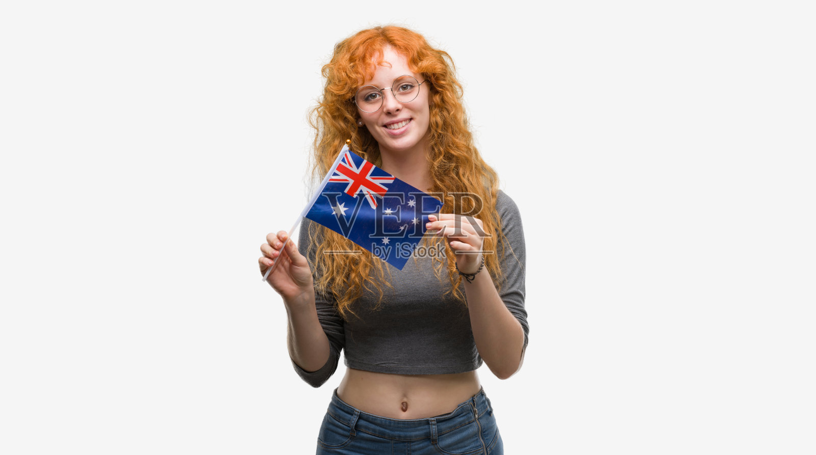 年轻的红发女子举着澳大利亚国旗，快乐的脸站在那里，自信的微笑着露出牙齿照片摄影图片