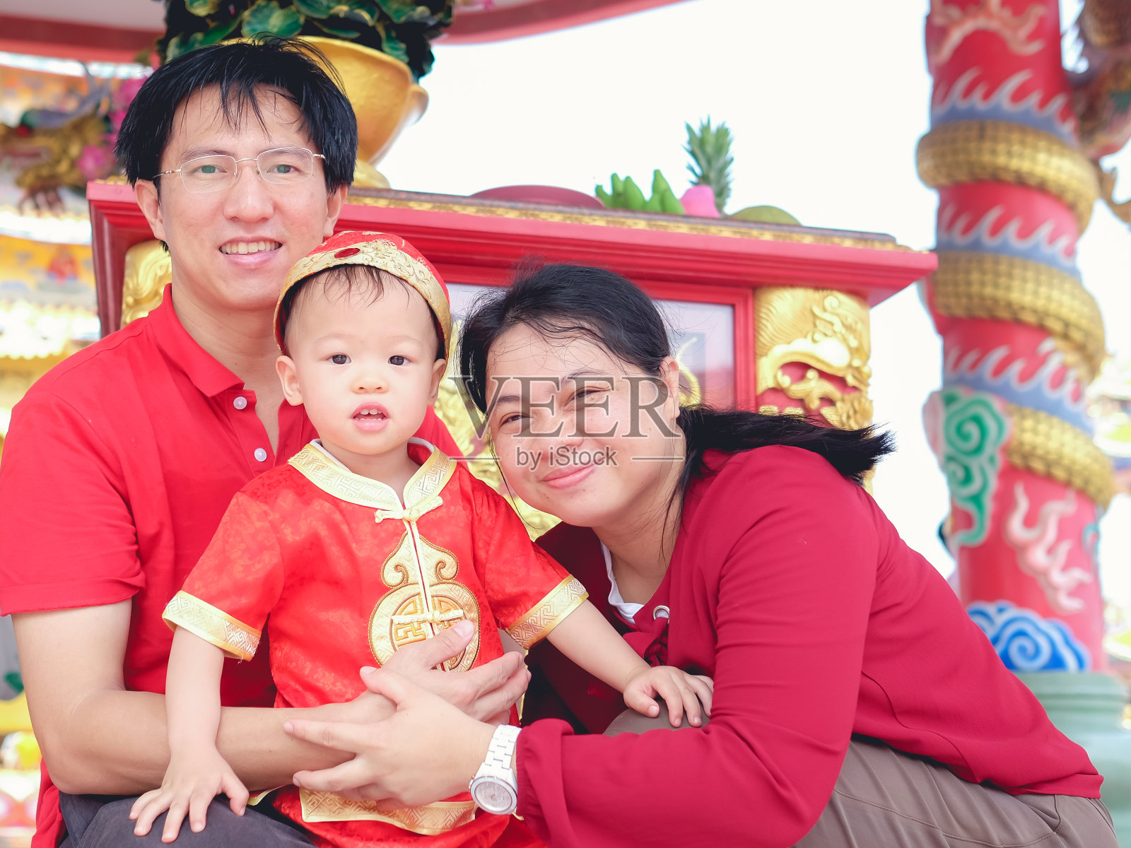 亚洲家庭庆祝中国新年，可爱的2岁小男孩穿着传统的红色中国服装在中国寺庙照片摄影图片