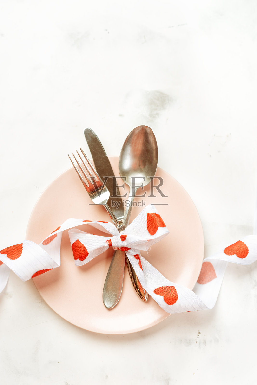 用餐具和粉色盘子为情人节准备的节日餐桌照片摄影图片