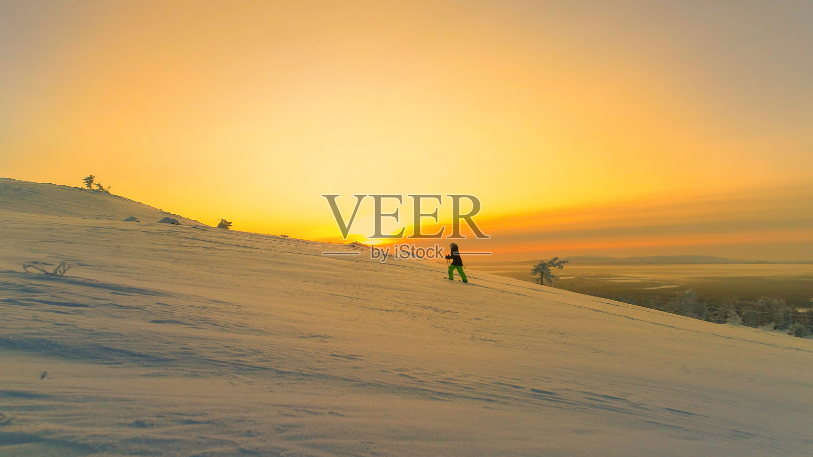 空中镜头:冬天日出时，飞向穿着雪鞋在雪山上徒步旅行的女人照片摄影图片
