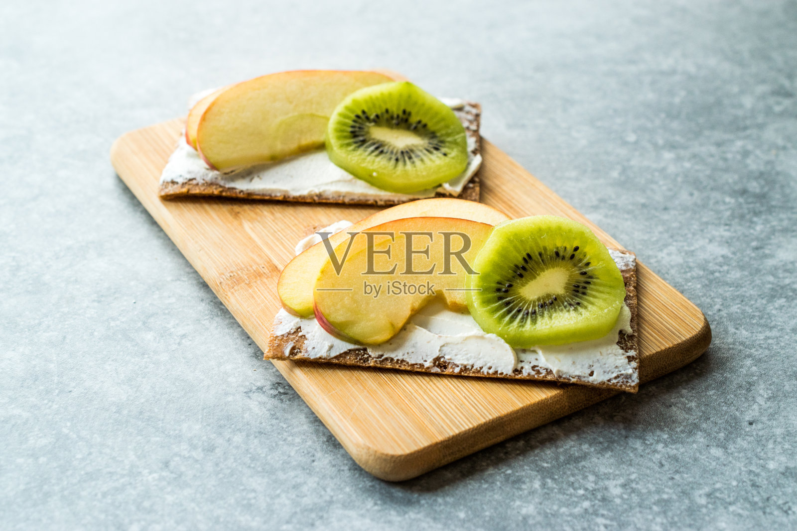 黑麦脆饼配奶油芝士，苹果片和猕猴桃/健康零食食谱。照片摄影图片