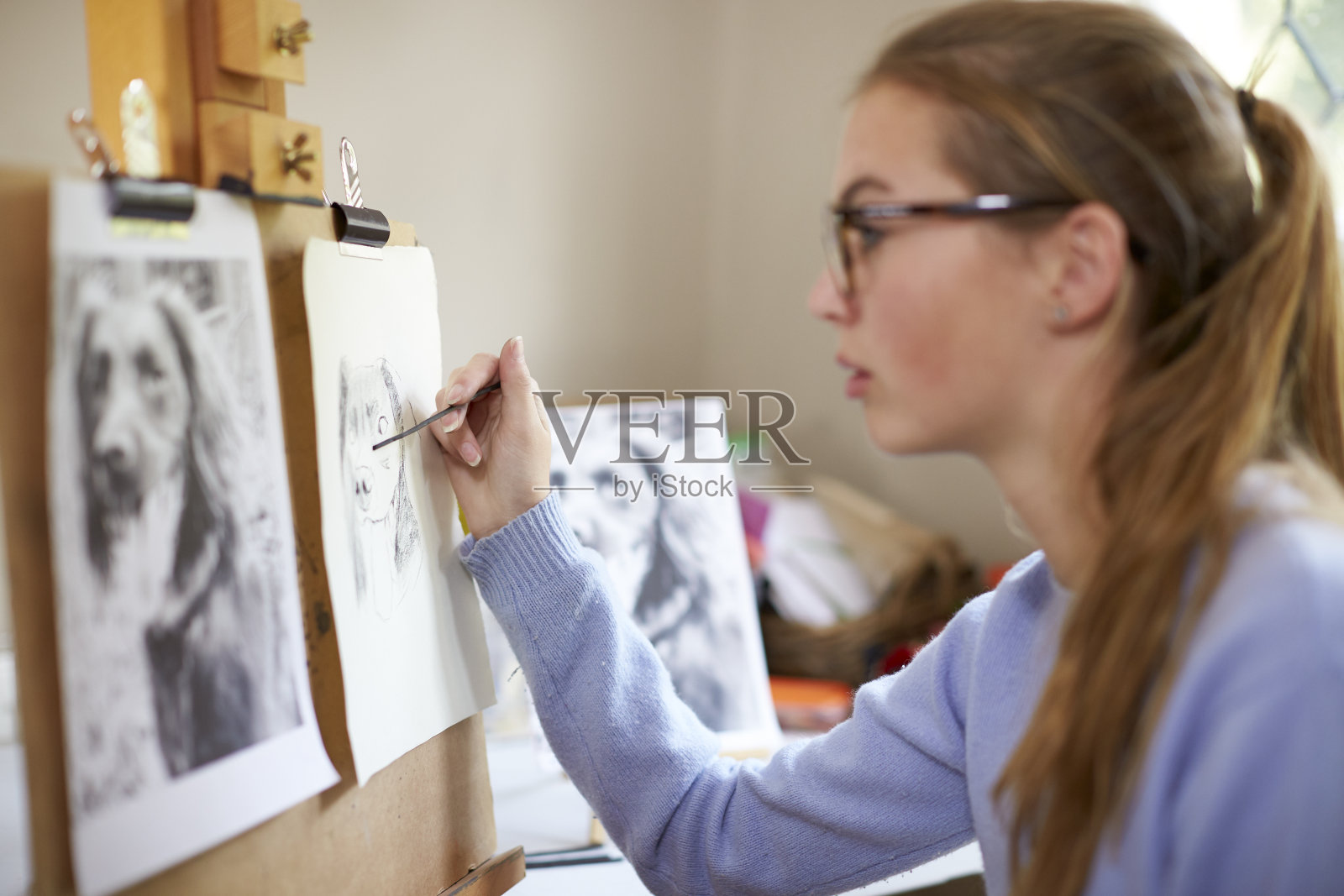 近距离的女性青少年艺术家坐在画架上画狗的照片在木炭照片摄影图片
