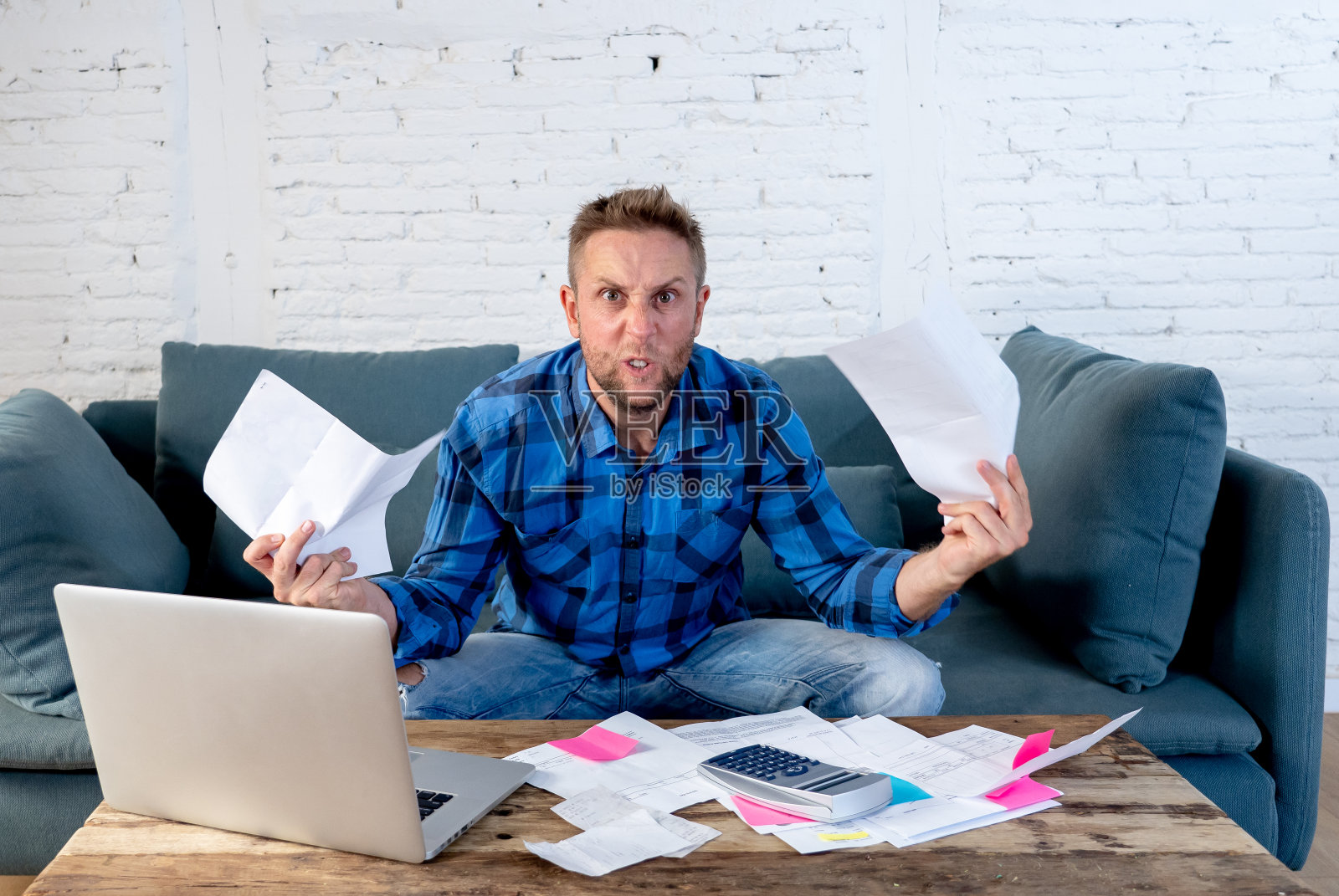 担心和紧张的男人计算账单，税收费用，计算家庭和商业财务坐在家里的沙发上偿还债务，国内账单和财务问题的概念。照片摄影图片