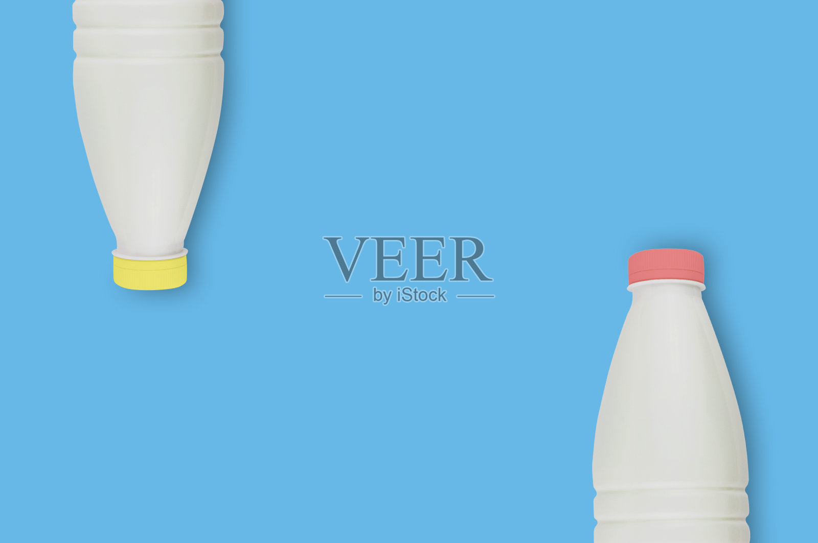 新鲜的乳制品，装在两个装满牛奶，开菲尔或酸奶的塑料瓶里，红色和黄色的盖子放在厨房的蓝色桌子上。为你的文本复制空间。前视图。烹饪概念照片摄影图片