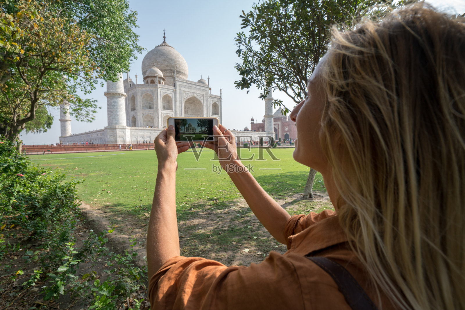 年轻女子用手机拍摄泰姬陵照片摄影图片