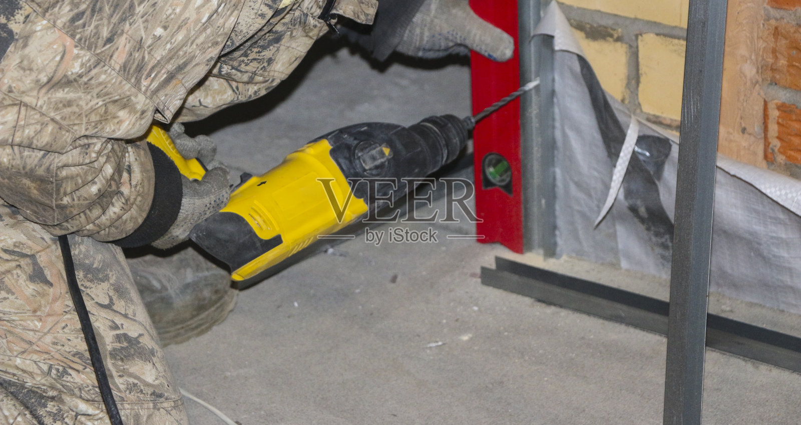 戴工作手套的男人在钢型材上钻孔，安装绝缘框架照片摄影图片