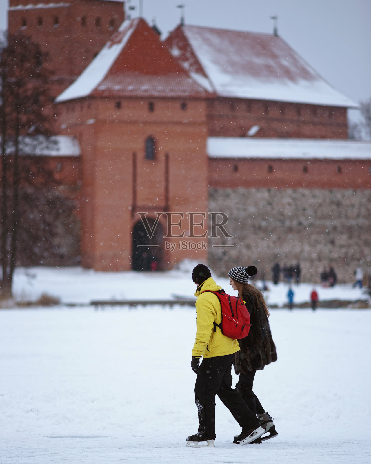 一对年轻夫妇在冬天的特拉凯冰湖上滑冰照片摄影图片