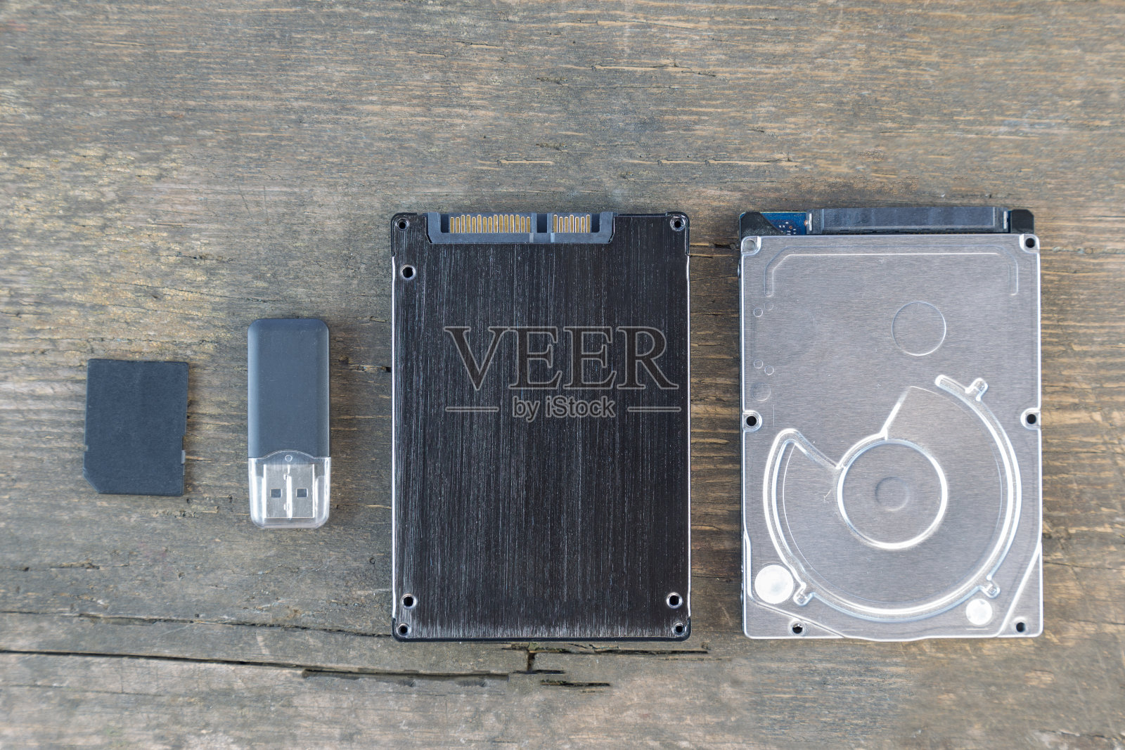 记忆进化的概念。在一个旧的木头背景上，平躺静止的硬盘驱动器，闪存驱动器和usb闪存棒照片摄影图片