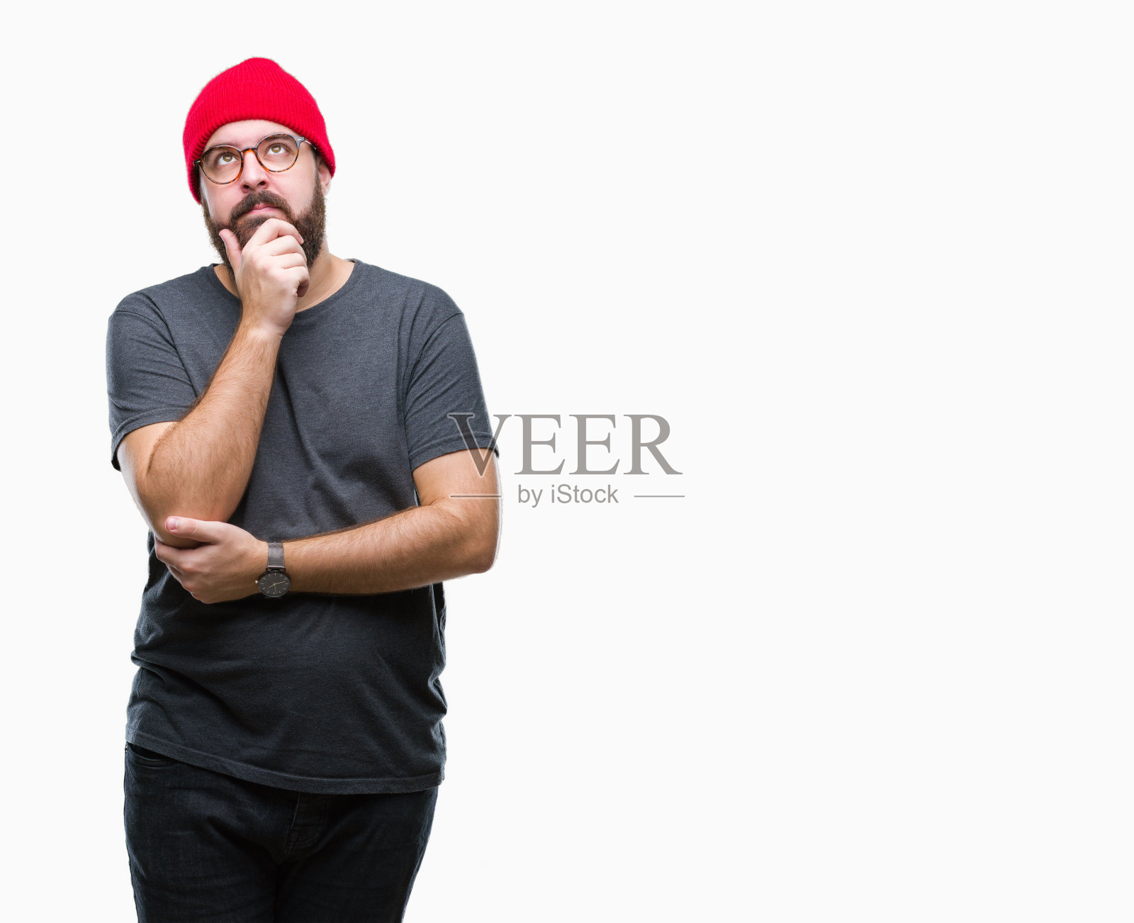 年轻的白人潮人戴眼镜在孤立的背景与手在下巴思考问题，沉思的表情。带着沉思的微笑。怀疑的概念。照片摄影图片