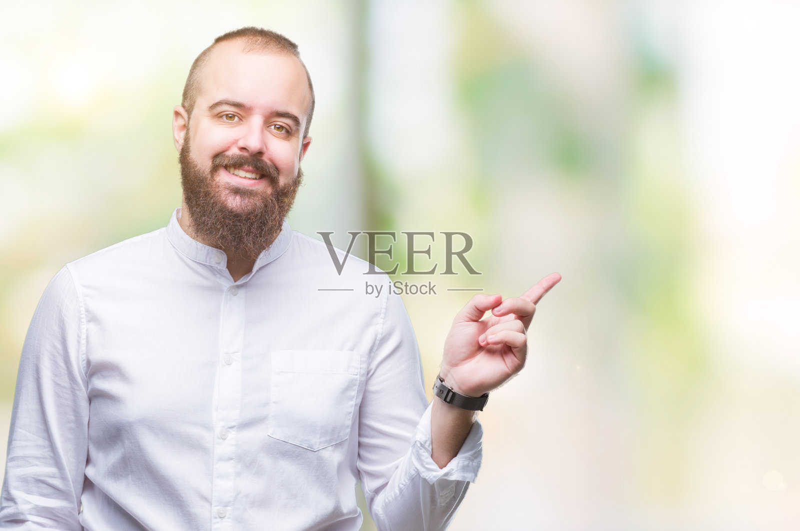 年轻的白人潮人在孤立的背景与一个大大的微笑在脸上，指着与手和手指的一边看镜头。照片摄影图片