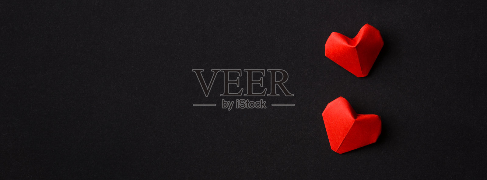 两颗红心在黑色背景上排成一排。副本的空间。极简主义。细长的格式照片摄影图片