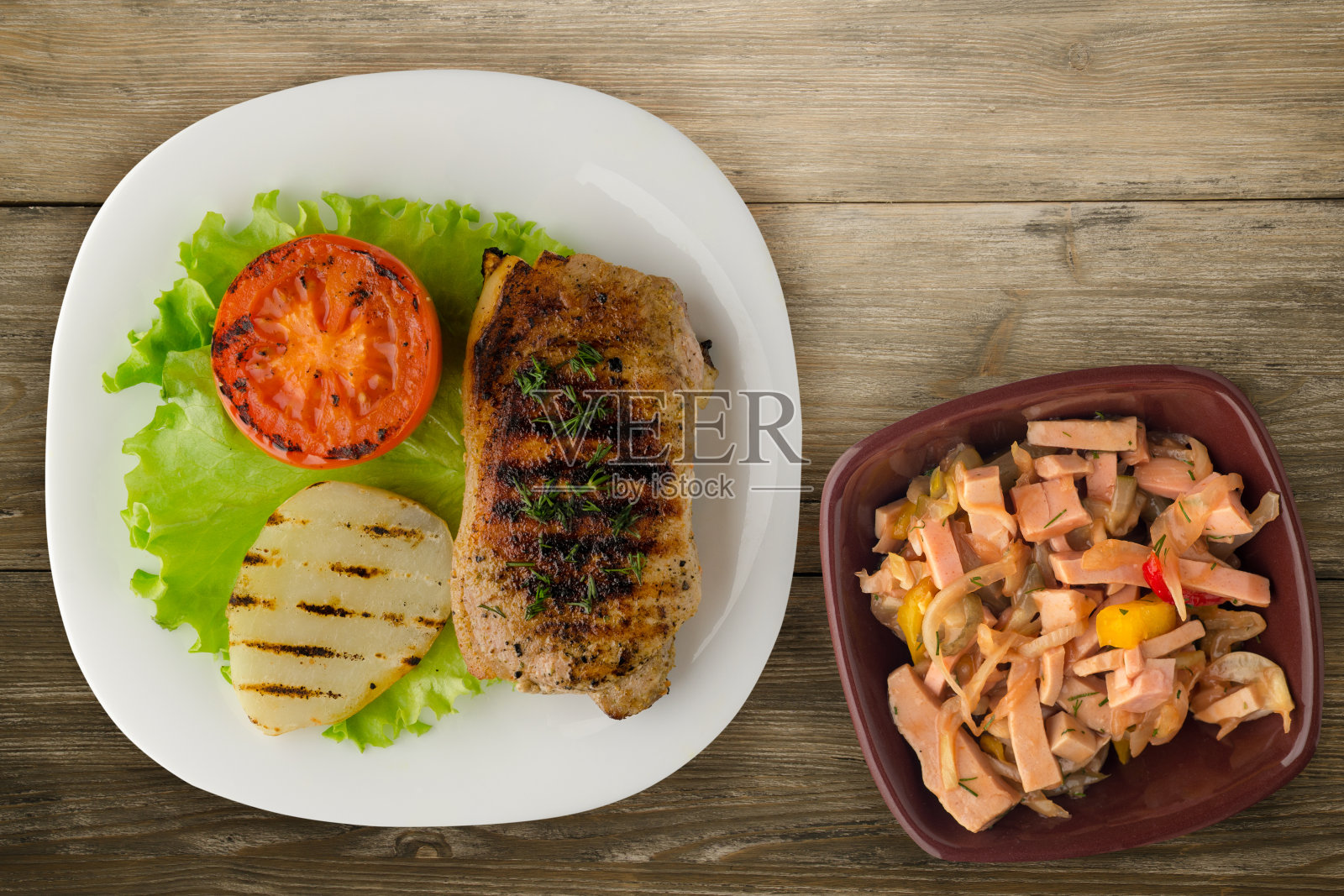 木背景上的土豆和番茄烤猪肉。盘子里的烤猪肉照片摄影图片