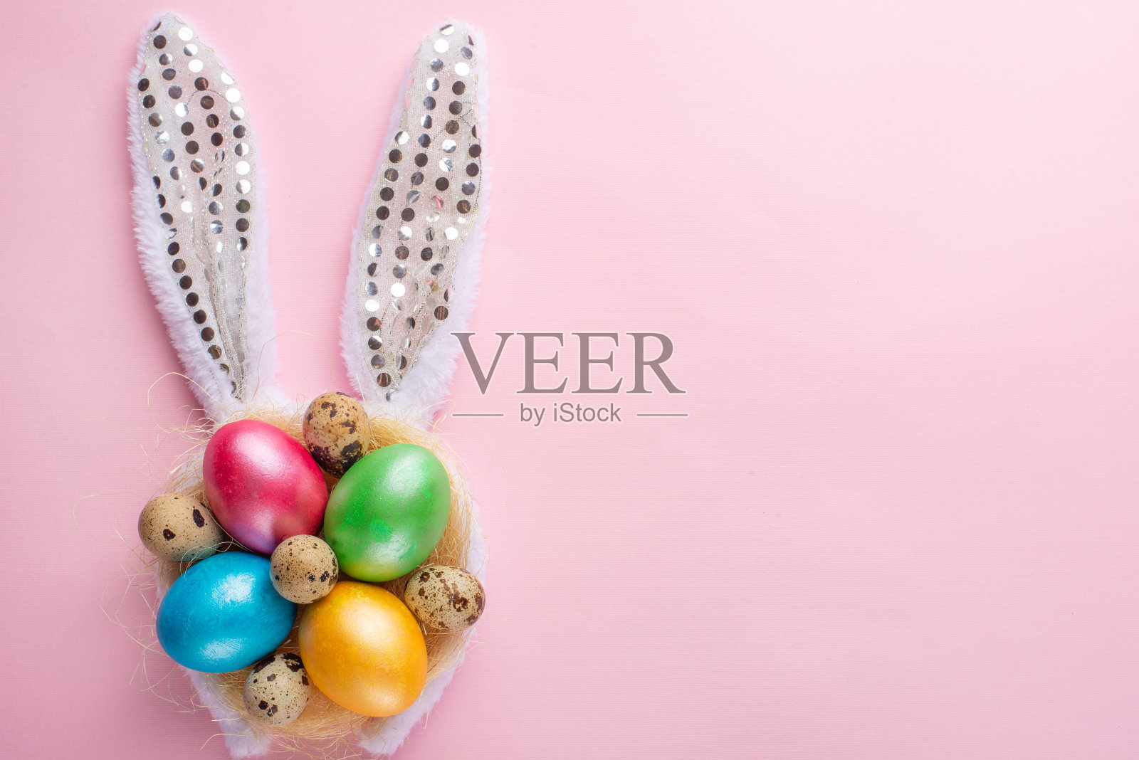 复活节的背景。复活节彩蛋与耳朵在粉红色的背景，水平组成。贺卡的概念照片摄影图片