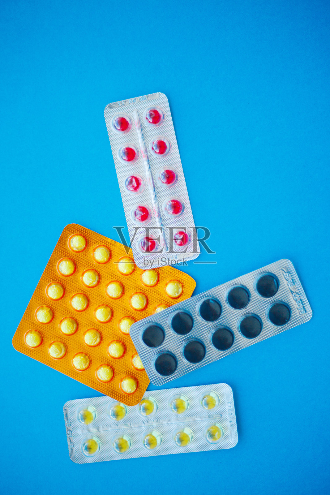 医学药。蓝色背景上的彩色药丸和胶囊。药房主题，胶囊药丸与药物抗生素包装照片摄影图片