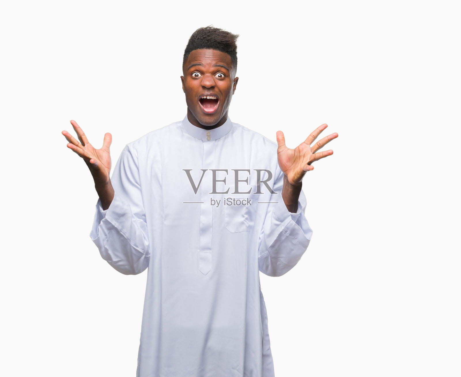 年轻的阿拉伯裔非洲人穿着传统的杰拉巴(djellaba)，在孤立的背景下庆祝疯狂和对成功的惊讶，举起手臂，睁开眼睛兴奋地尖叫。赢家的概念照片摄影图片