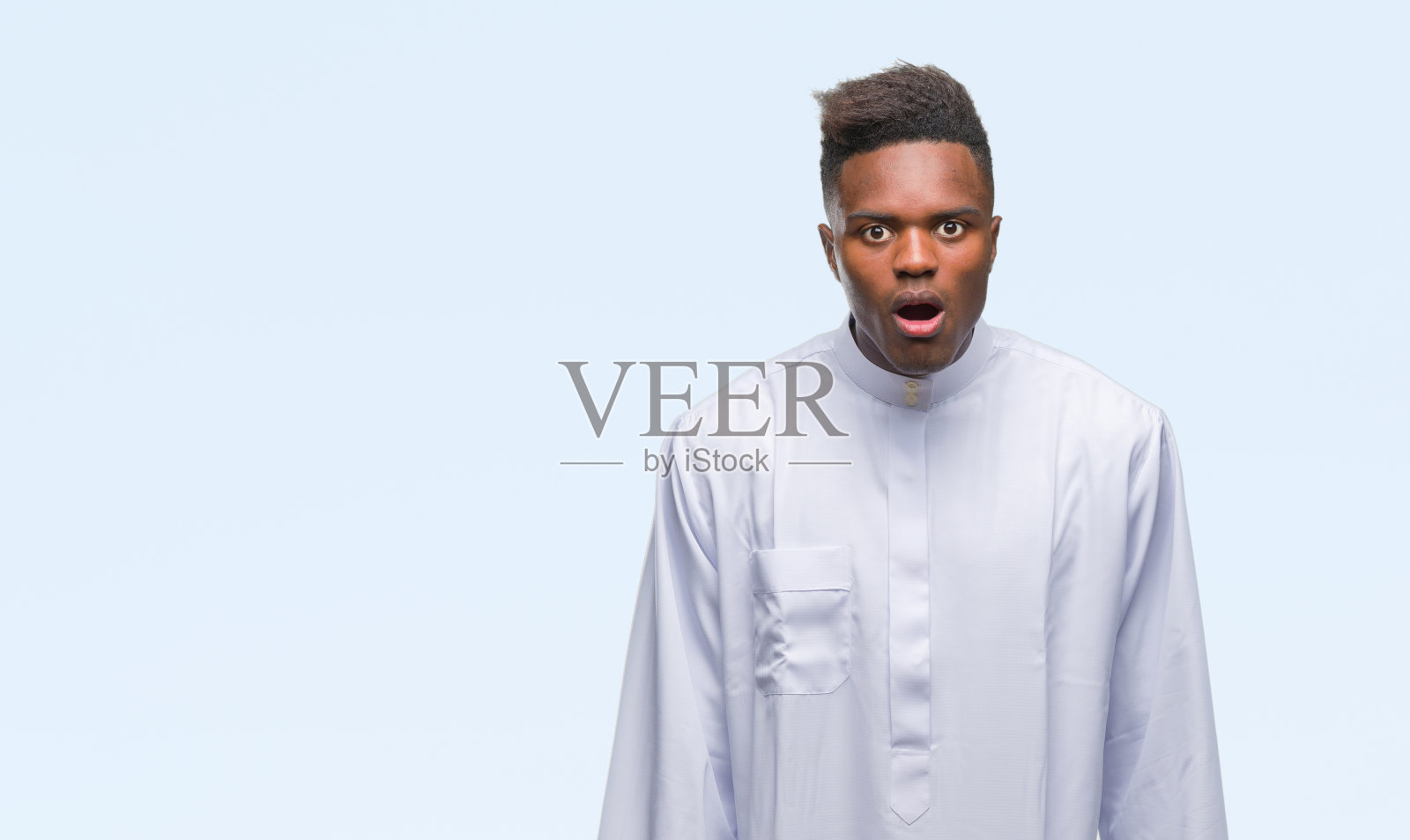 年轻的阿拉伯裔非洲人穿着传统的djellaba在孤立的背景害怕和震惊与惊讶的表情，恐惧和兴奋的脸。照片摄影图片