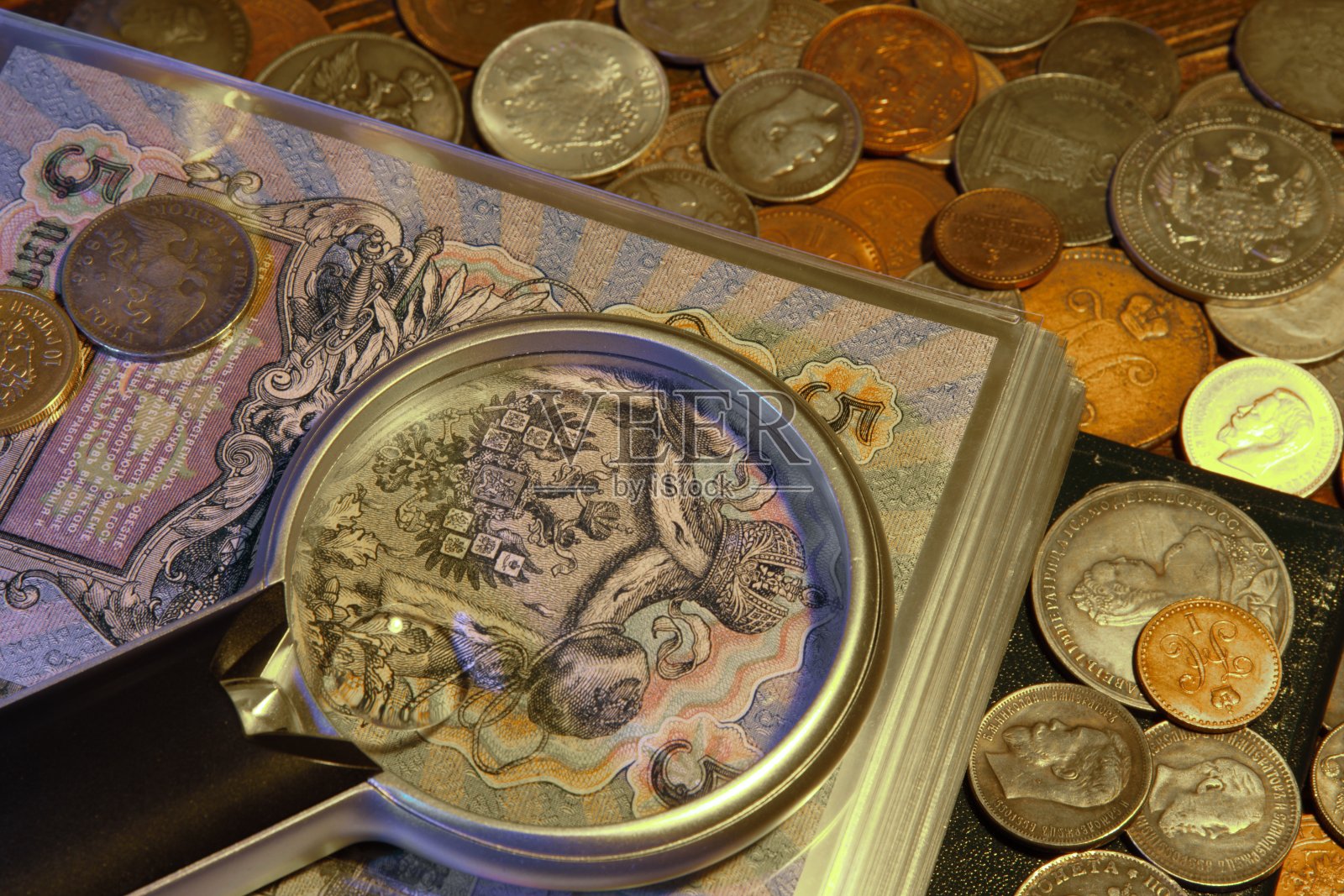 用放大镜看旧钱和硬币。钱币和收集钱。俄罗斯帝国和世界货币，银，金。照片摄影图片