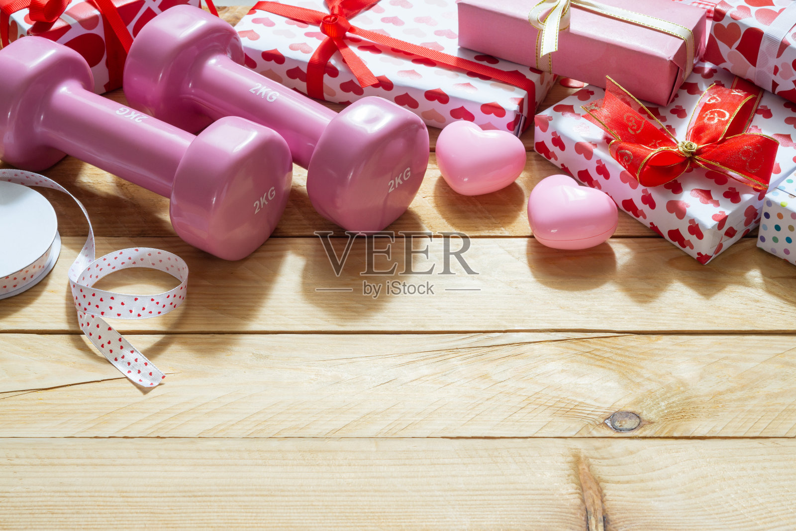 粉色运动哑铃，心形模型和木制背景上的礼盒，情人节运动背景和贺卡的任何周年节日背景概念。照片摄影图片