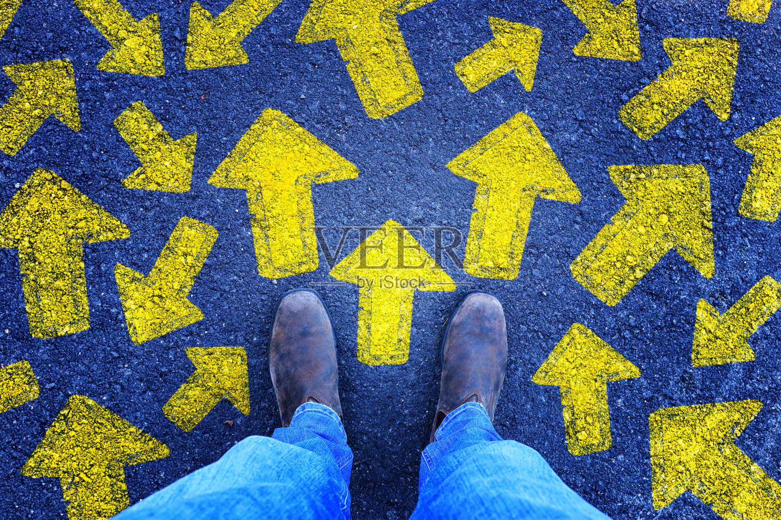 俯视图照片的人在牛仔裤和复古的鞋子站在沥青路面与绘制箭头显示不同的方向。过滤掉。照片摄影图片