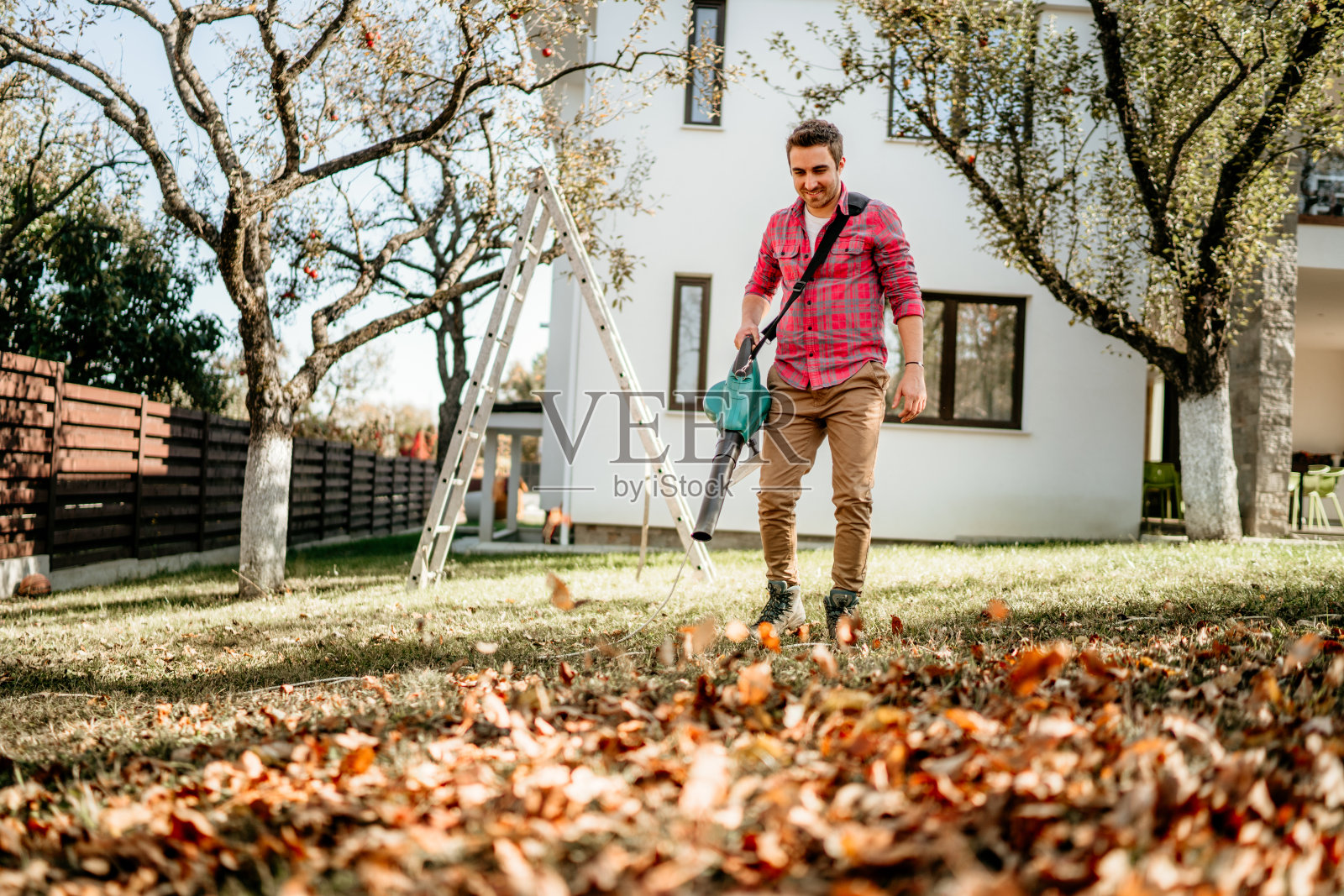 男性使用花园吹风机的肖像，家庭园艺细节照片摄影图片