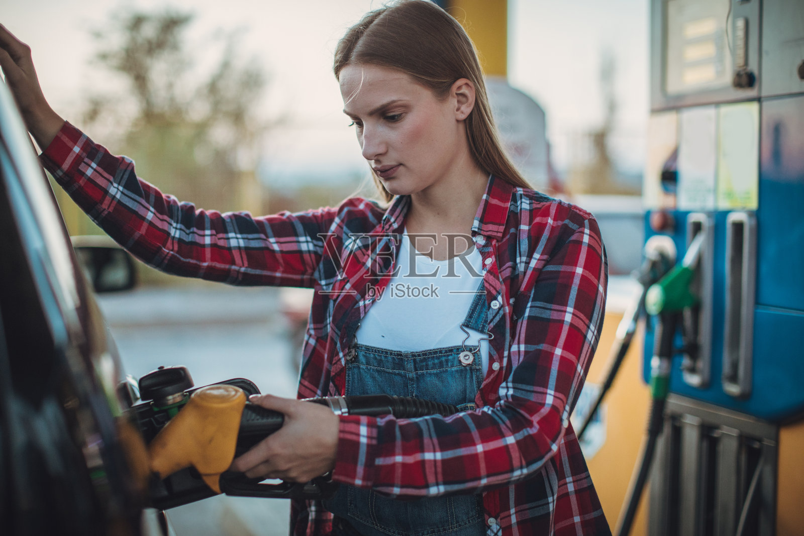 年轻女士往车里加油照片摄影图片