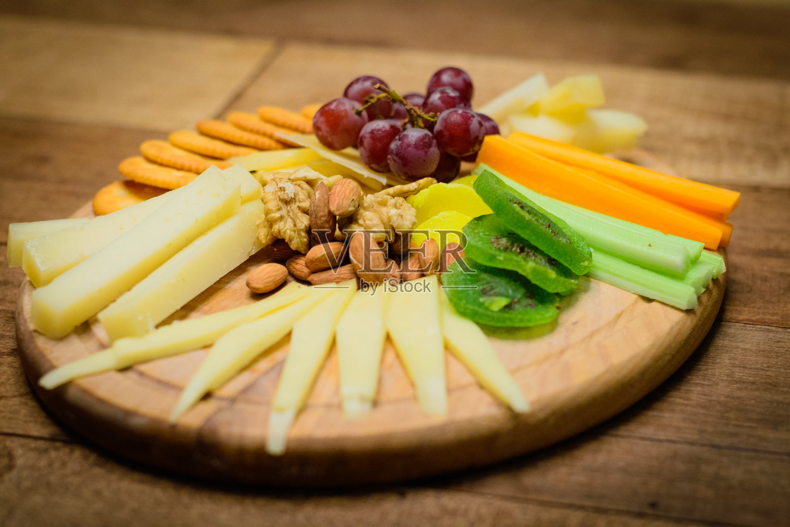 奶酪拼盘与4种奶酪，榅桲膏，无籽葡萄，胡萝卜，芹菜蔬菜和杏干。照片摄影图片