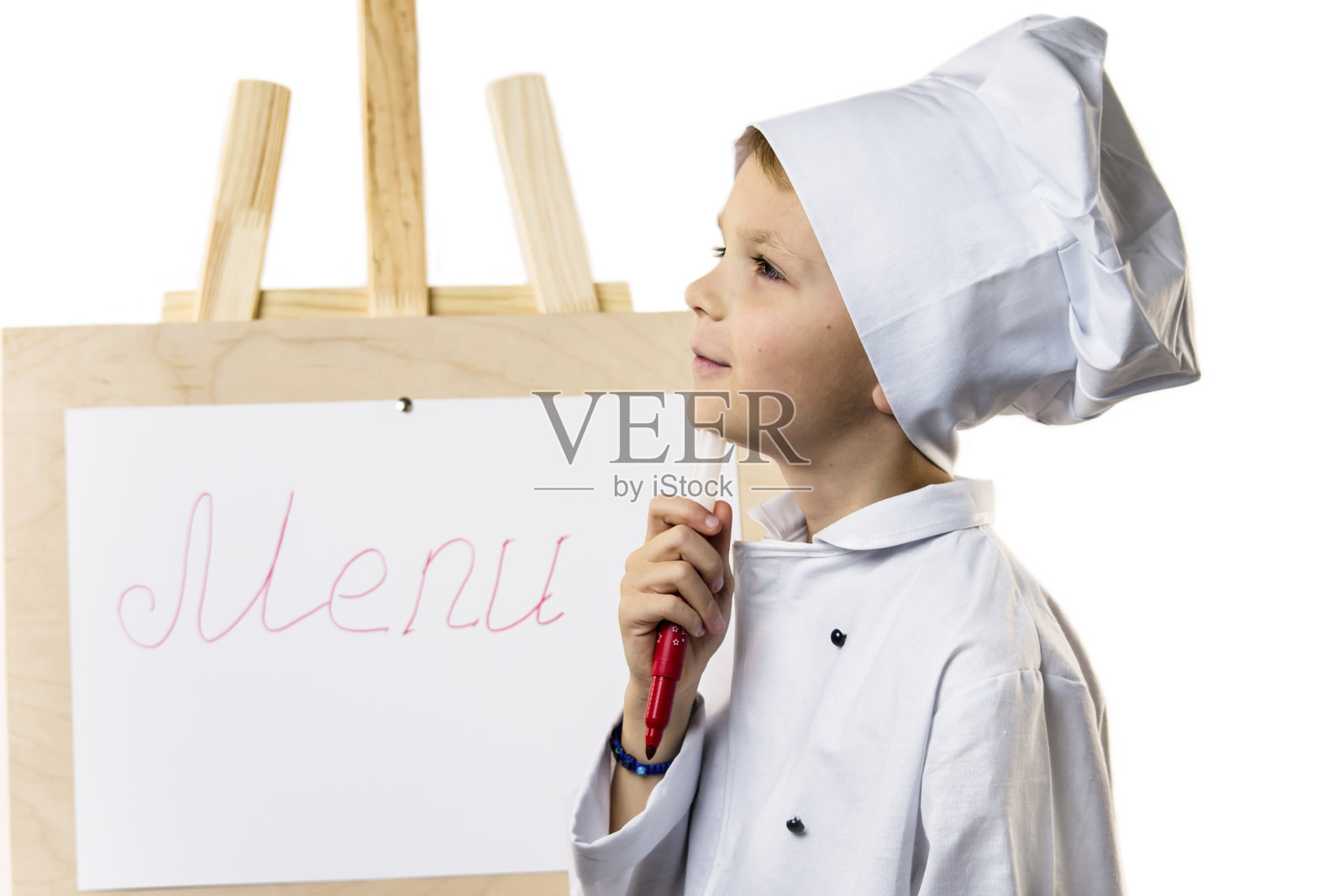 穿着厨师服的可爱男孩在纸上准备菜单照片摄影图片