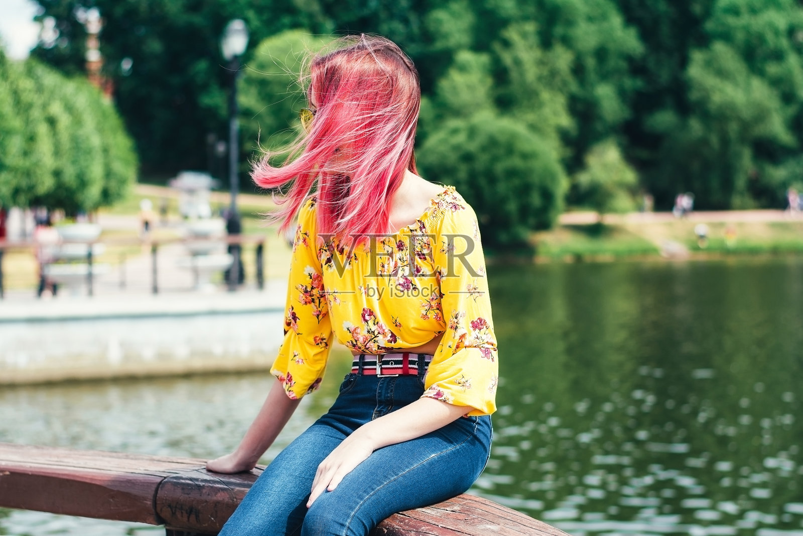 在夏天的公园里，有一头粉红色头发的年轻美丽的女孩照片摄影图片