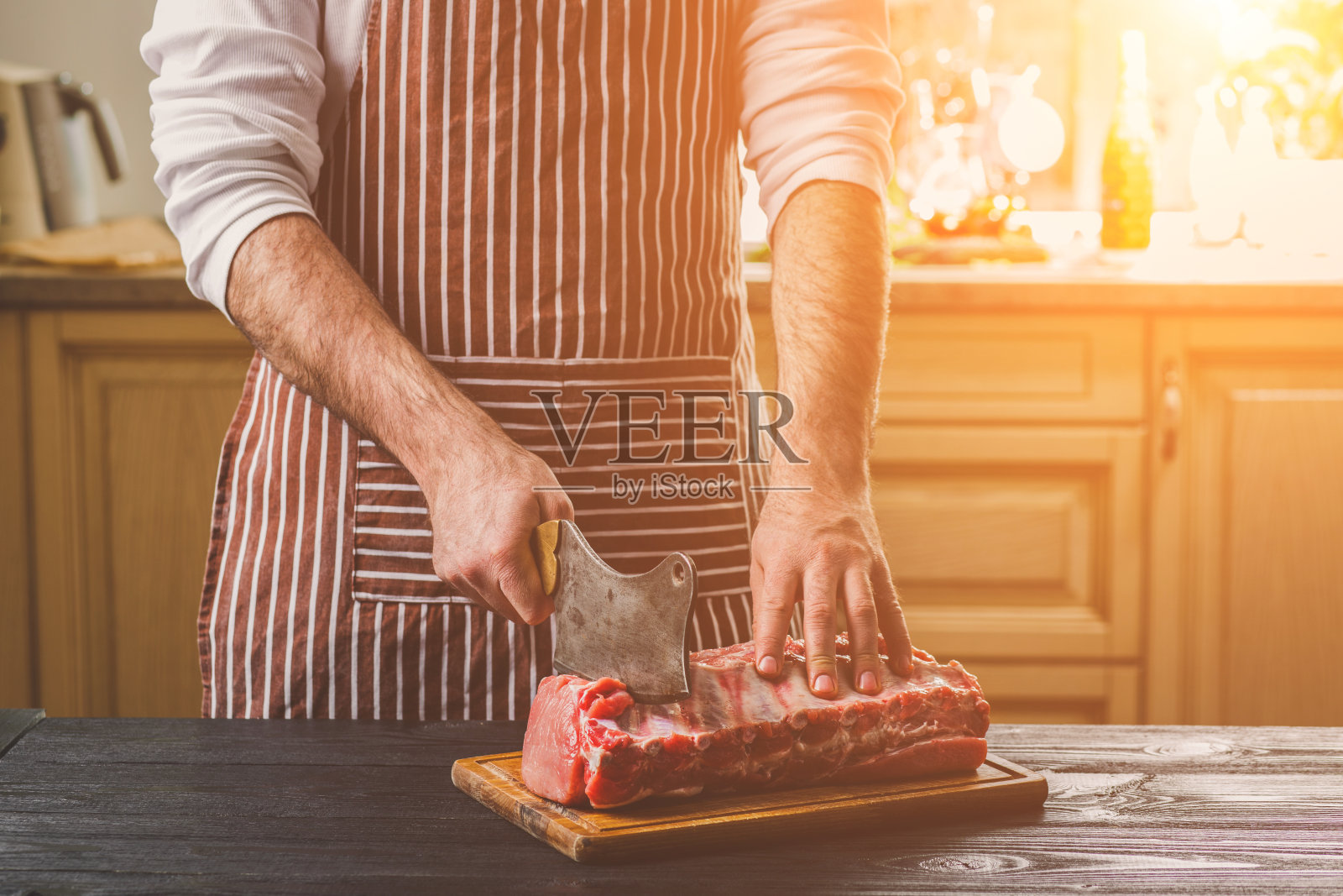 男人在家庭厨房的木板上切新鲜的牛肉块照片摄影图片