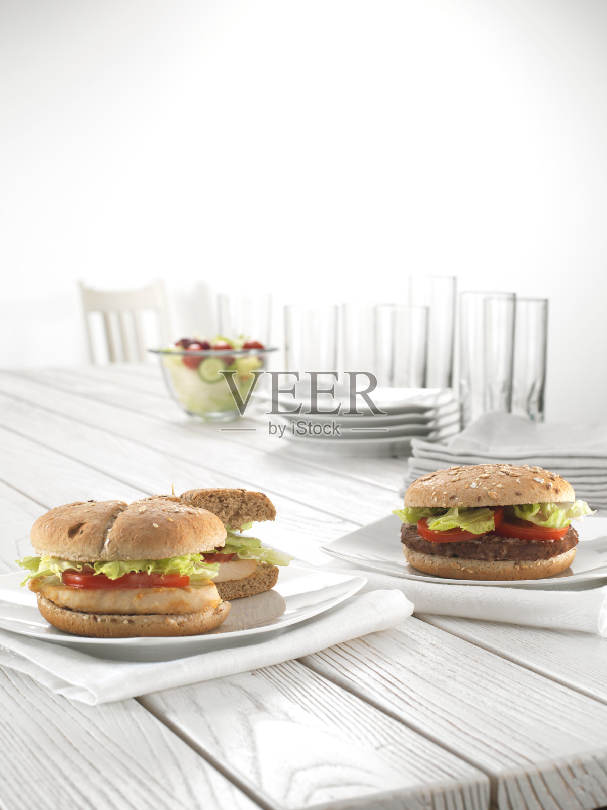 鸡肉和肉类汉堡和沙拉在碗和盘子在白色木制桌子上。照片摄影图片