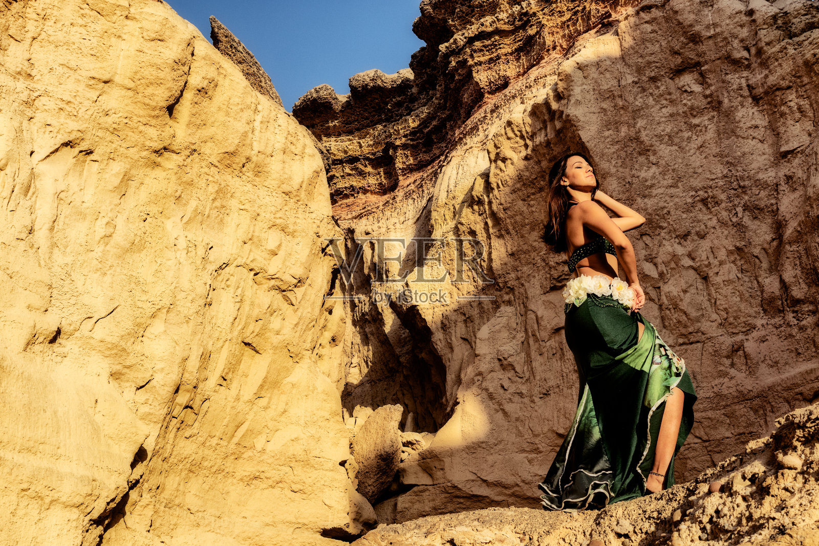 在纳米贝沙漠峡谷的神秘空间里，身着绿色裙子的年轻女孩正在跳着著名的肚皮舞。非洲。安哥拉。照片摄影图片