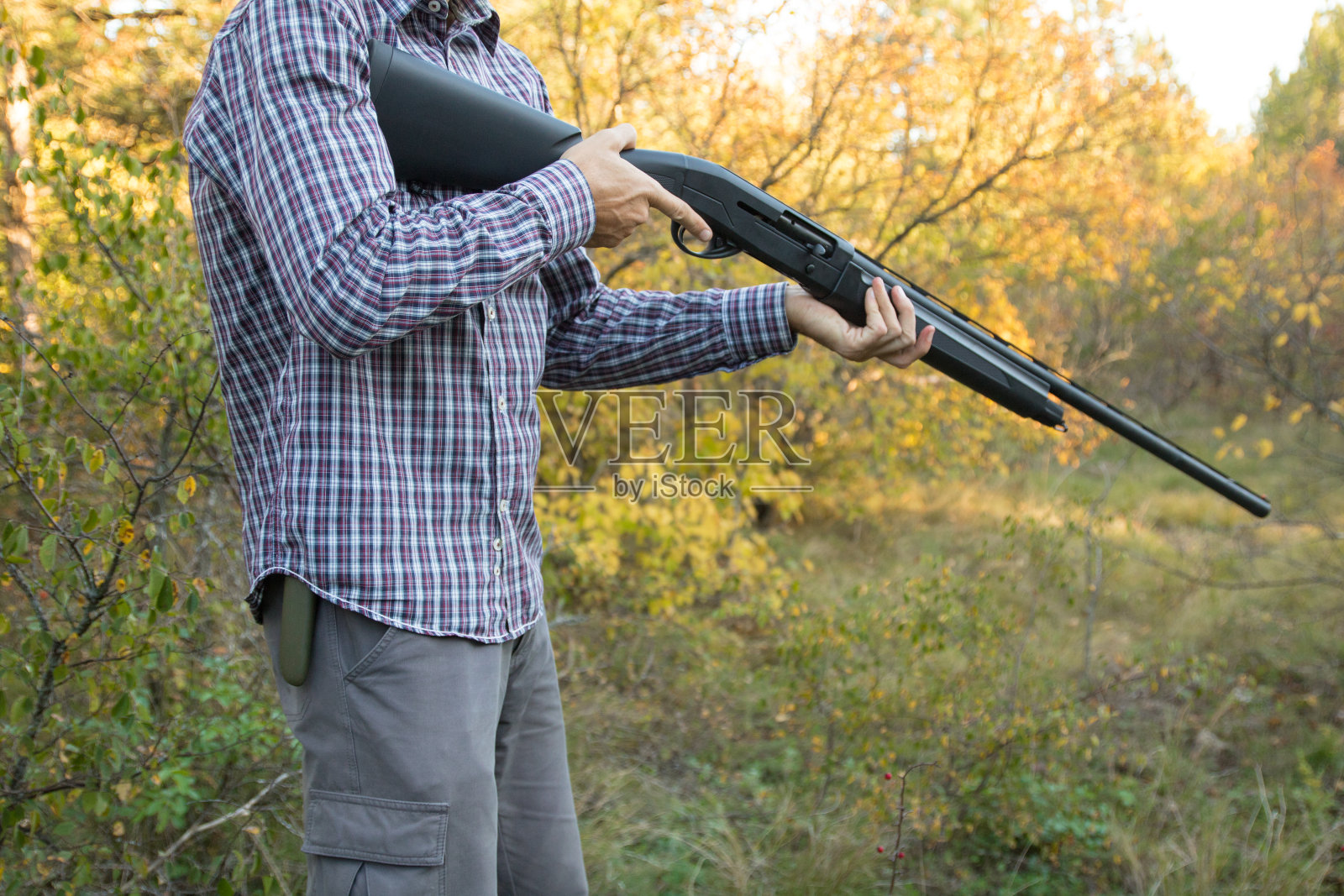 男性拿着半自动猎枪在秋天的森林里准备狩猎，近景照片摄影图片