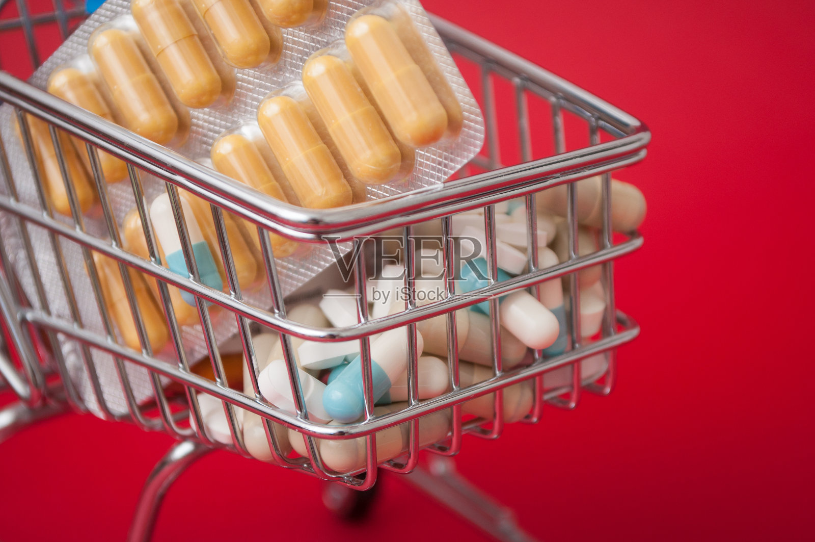 红色背景上超市购物车中的药品、药丸和胶囊照片摄影图片