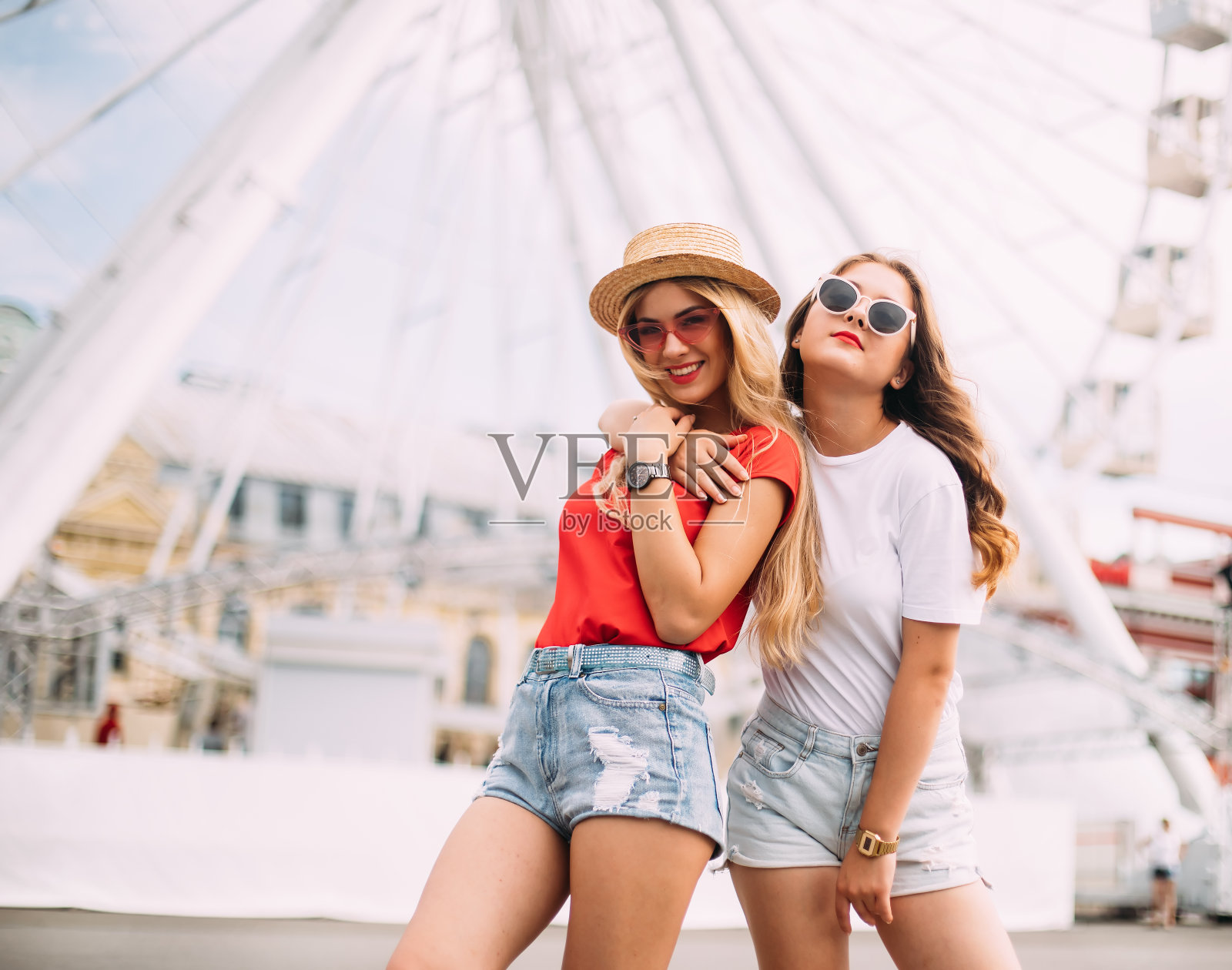 两个时尚女孩在大街上拥抱的快乐、欢快、积极的时刻。特写肖像滑稽快乐迷人的年轻女人有乐趣，微笑，可爱的时刻，最好的朋友照片摄影图片