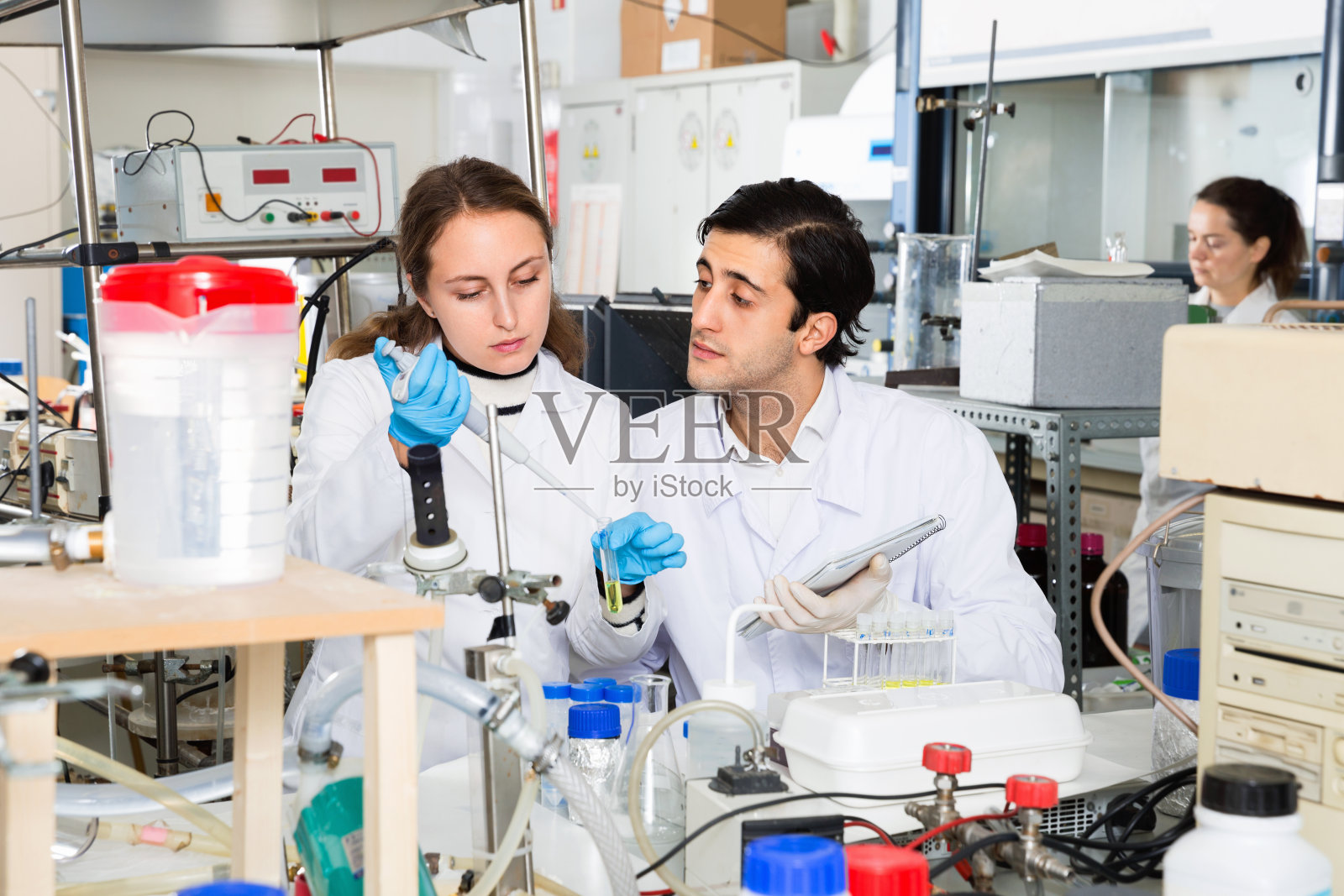 两个年轻的科学家在实验室一起工作，把化学实验的结果写在笔记本上照片摄影图片