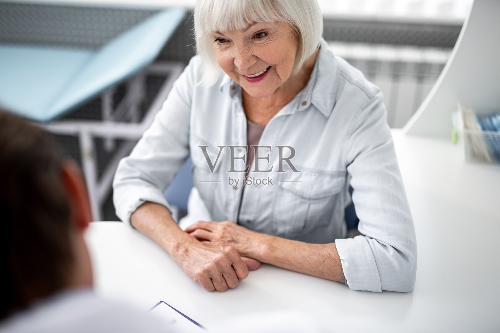 情绪化的老妇人坐在桌旁微笑着照片摄影图片