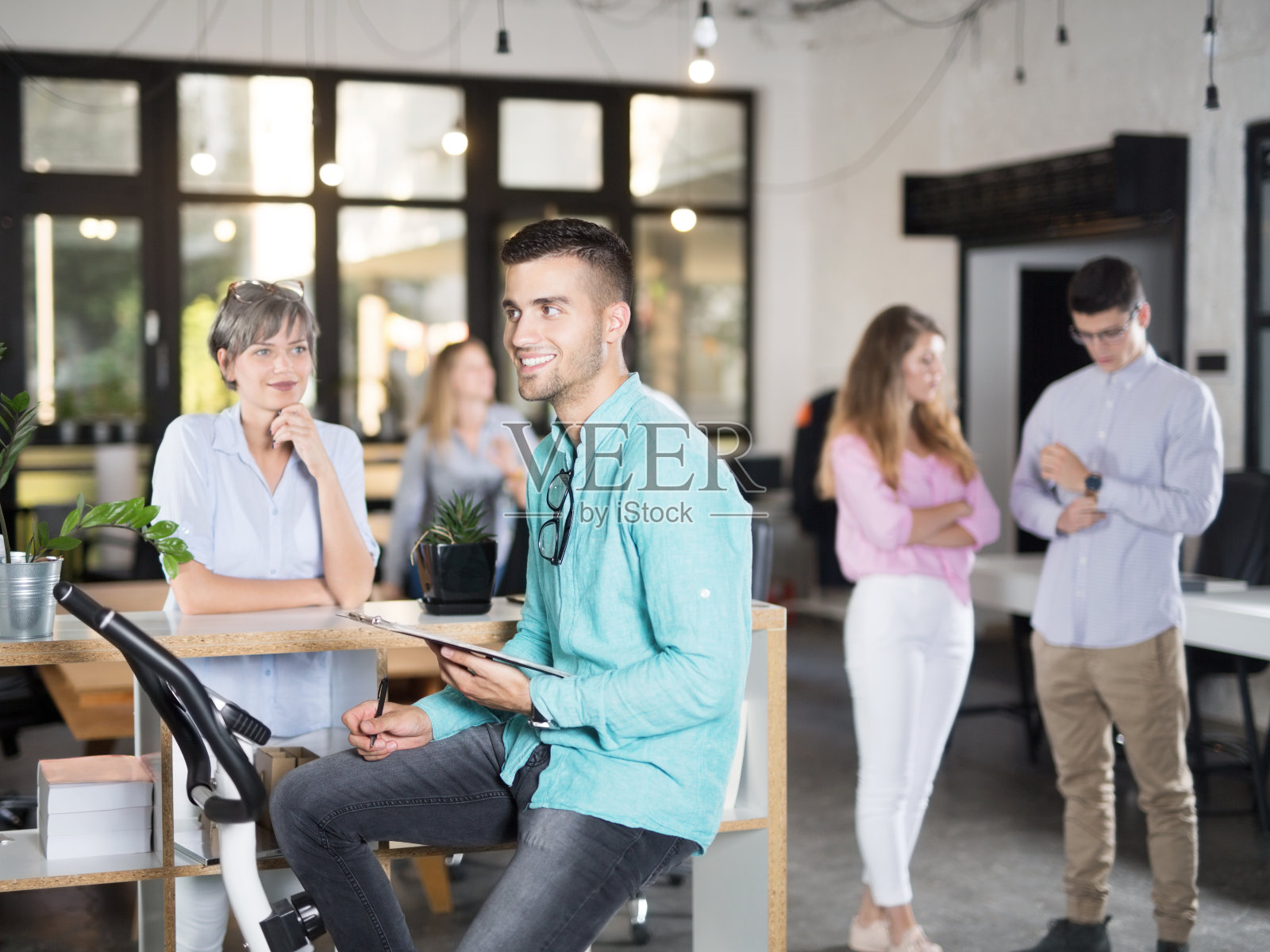 年轻的商人微笑着坐在训练自行车上照片摄影图片