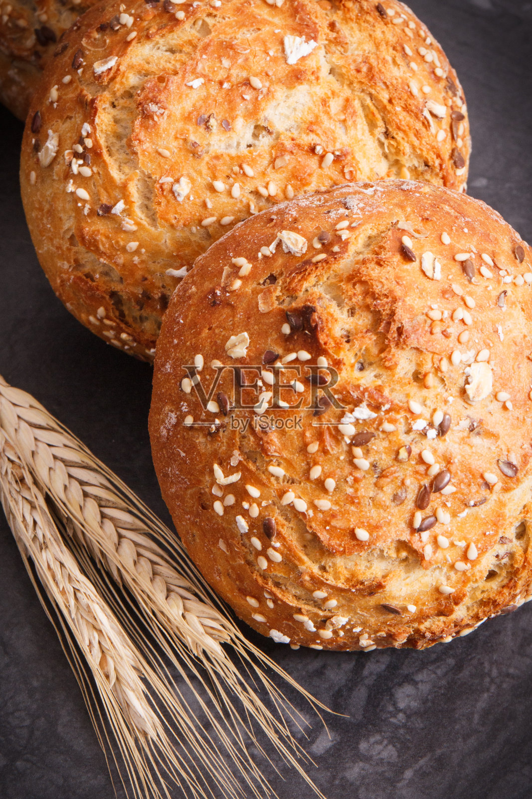 新鲜烘焙的自制面包卷，里面有黑麦或小麦的种子和穗子照片摄影图片